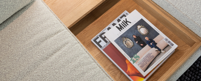 Eltern sitzen entspannt auf dem beigen Sofa, Kind spielt am Couchtisch