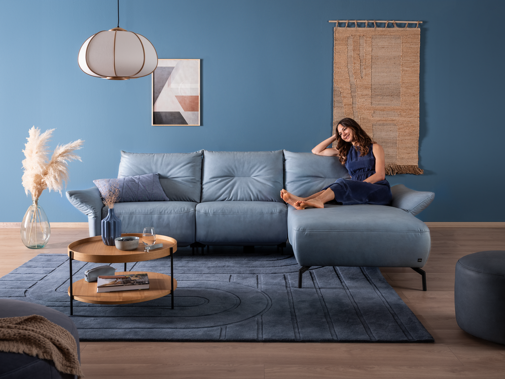 Frau lehnt entspannt auf dem blauen Sofa SALVIA mit Chaiselongue