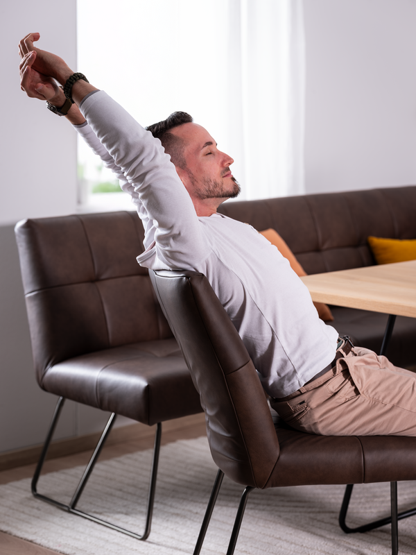 Ein Mann lehnt sich im Esszimmerstuhl ANI in die Lehne mit ADAption-Funktion