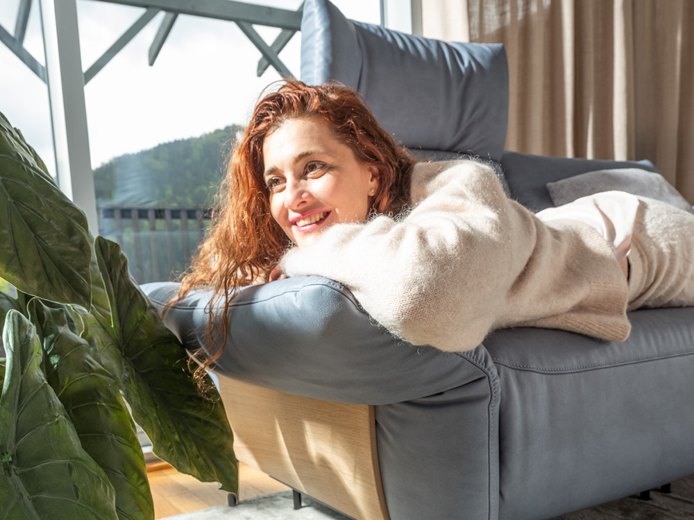 Frau genießt Sonnenstrahlen auf Couch SALVIA