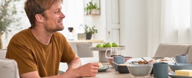 Mann sitzt beim Frühstückstisch
