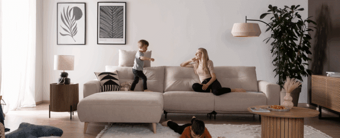 Frau spielt mit 2 Kindern auf dem Sofa Alika