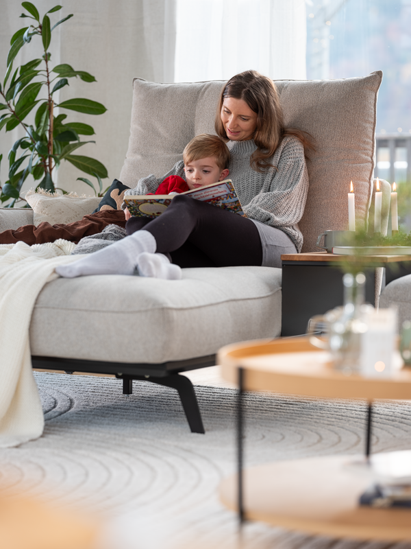 Mutter und Sohn kuscheln auf der Couch und lesen ein Buch