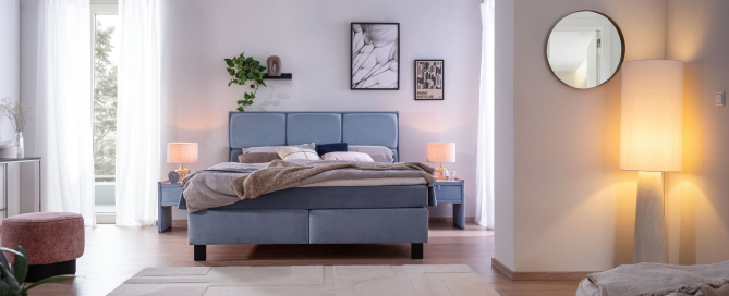 Bett Sidus in hellblauem Stoff, schwarzen Metallfüßen und Steppung im Kopfteil und mit Topper in hellem Schlafzimmer