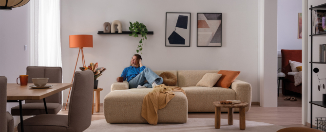 Frau entspannt auf der Couch PINEA in kleinem Wohnraum.
